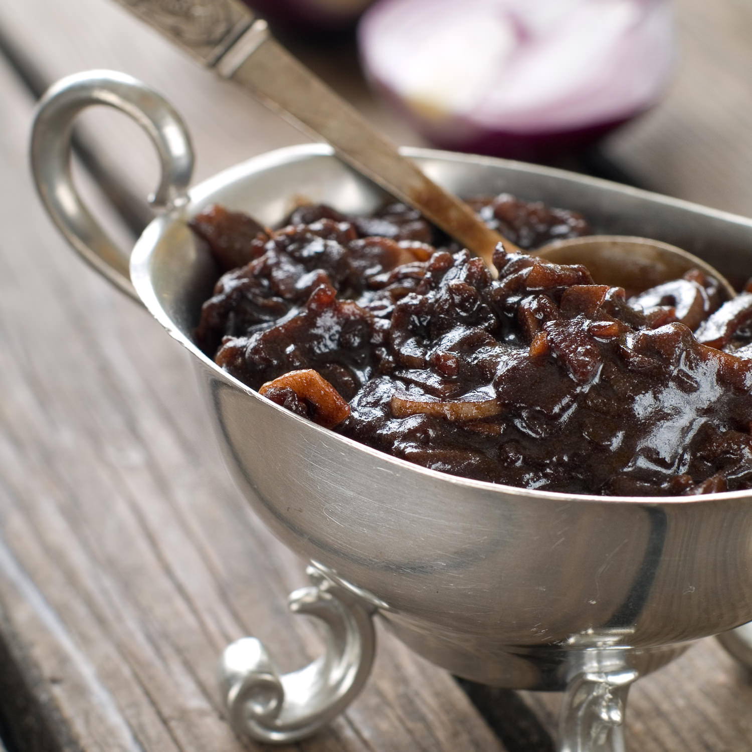 Composta scura di cipolle caramellate servita in salsiera d’argento.