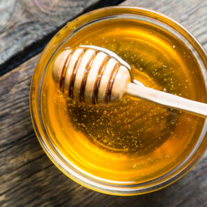 Ciotola di miele di acacia con cucchiaio in legno