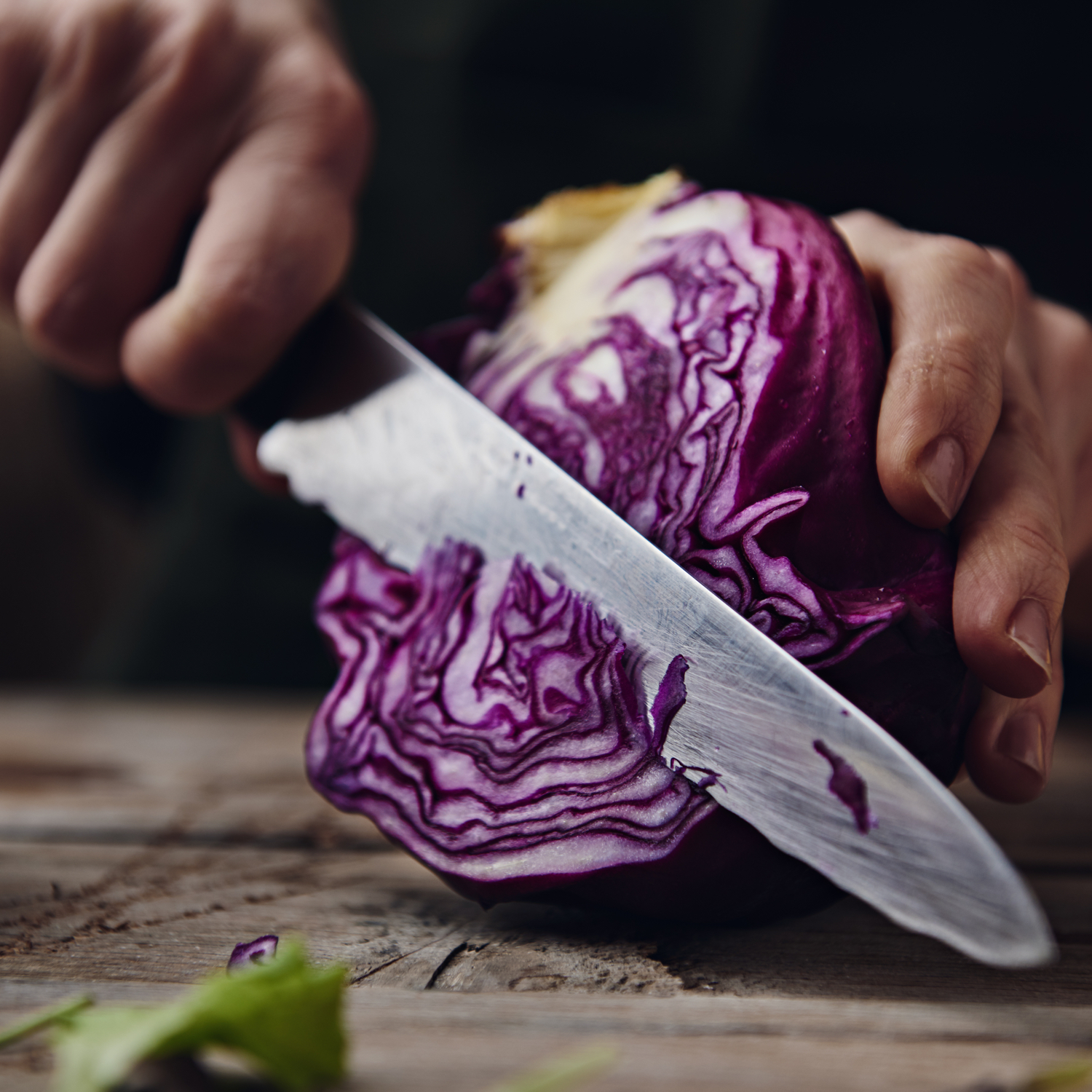 Mano che taglia un cavolo rosso fresco con un coltello