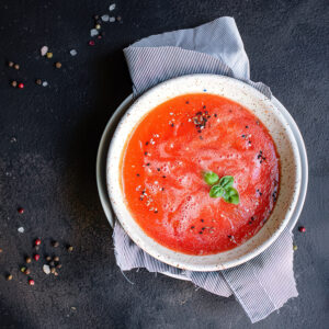 vellutata di pomodoro con basilico in ciotola bianca